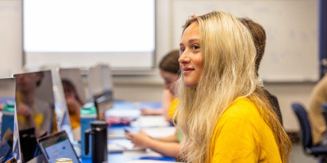 RMC student sits at computer, looking over at Math professor.