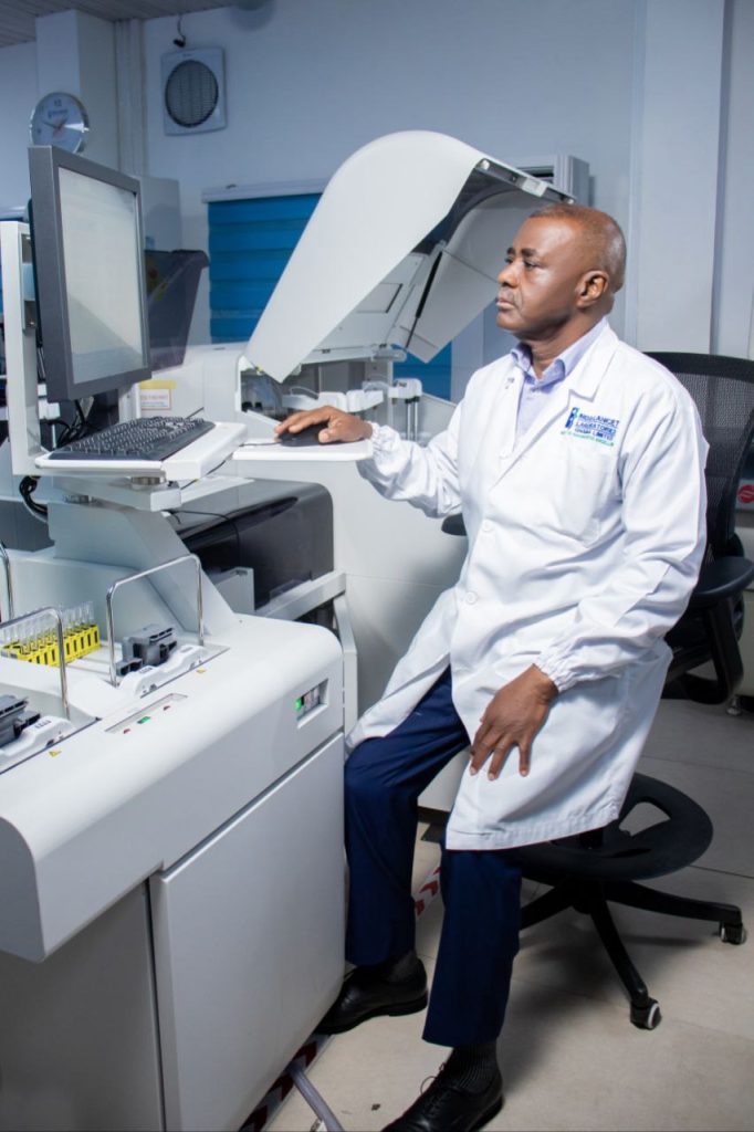 A person operates laboratory equipment and monitors data on a computer screen in a laboratory.