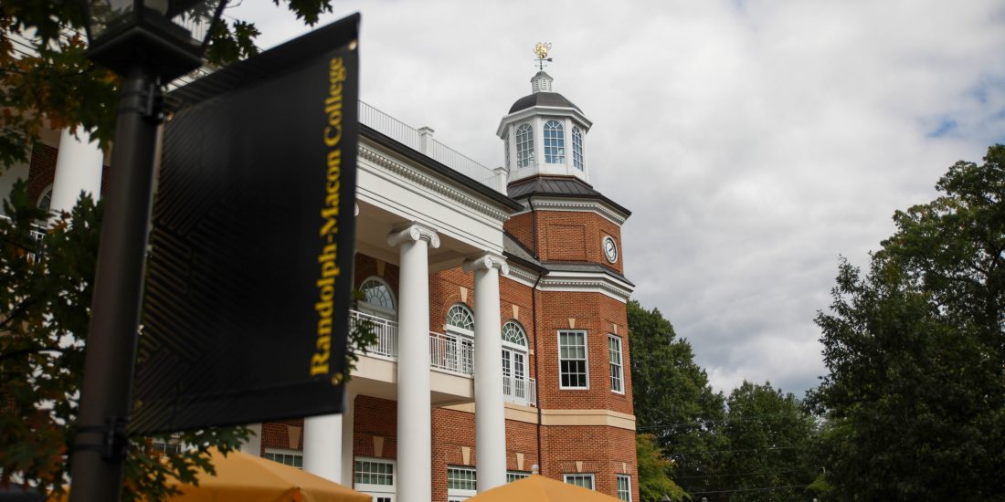 A building with white columns, with a banner and umbrellas visible.