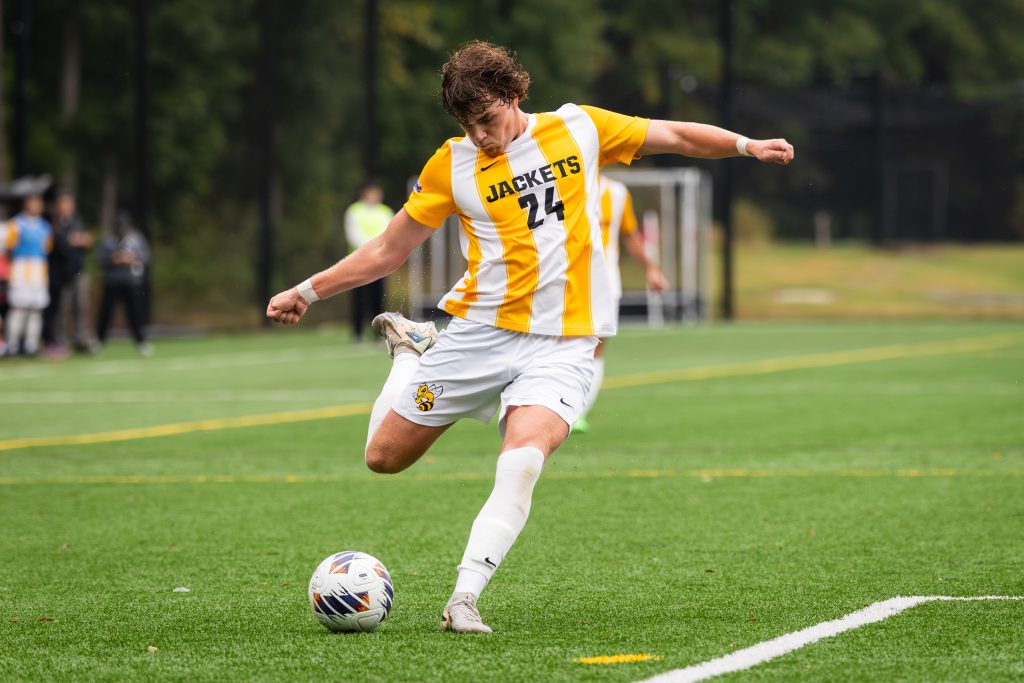 A soccer player kicks a ball on an outdoor field during a game.