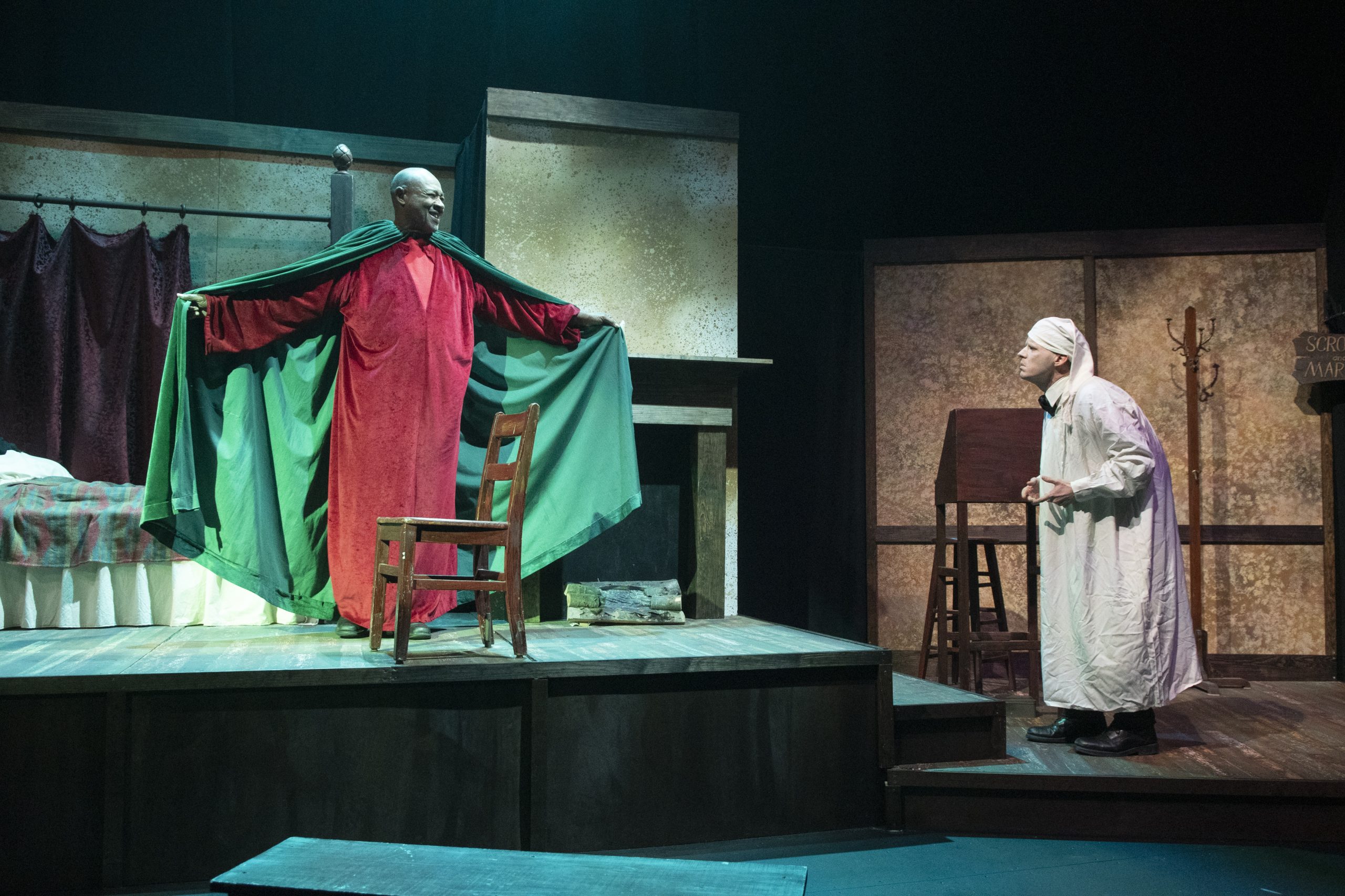 Two performers on stage enact a scene from A Christmas Carol