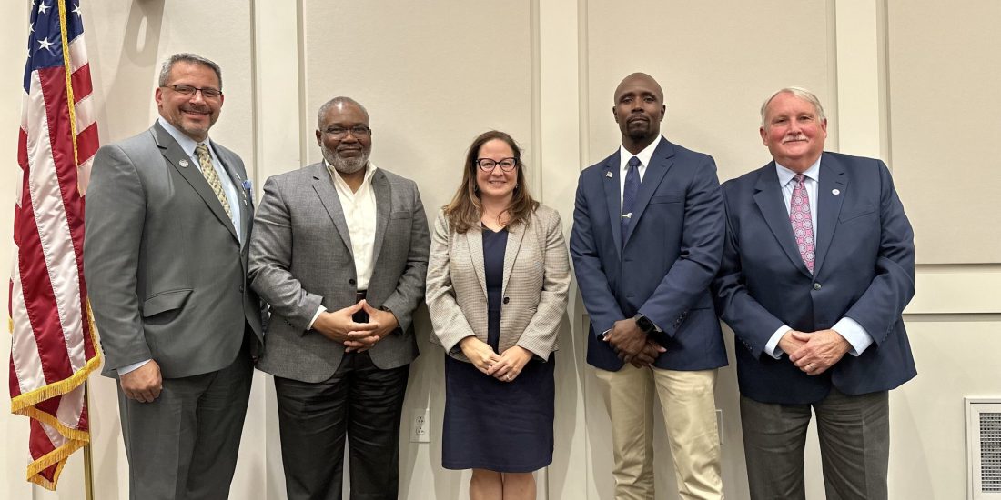 Dr. Lauren Bell and the four Ashland Town Council candidates standing in front of a wall and a U.S. flag inside Ashland Town Hall.