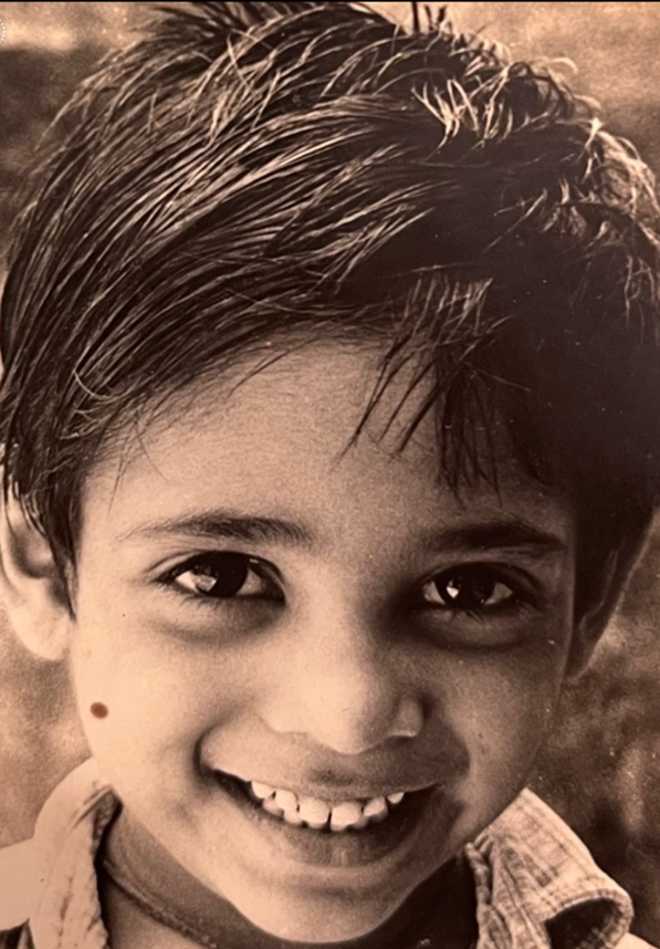 A person smiles at the camera in a black and white photo.