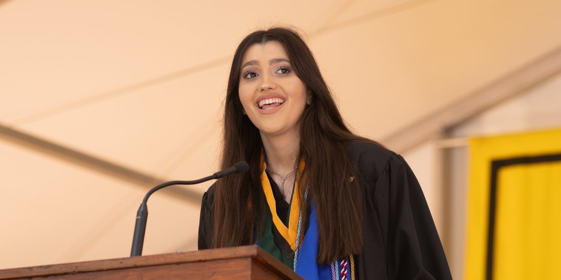 A graduate speaks at a podium during commencement.