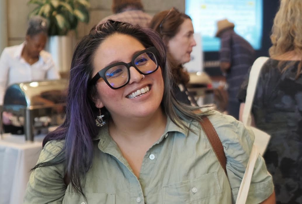 Emma Ito smiles at a function in a room full of people.