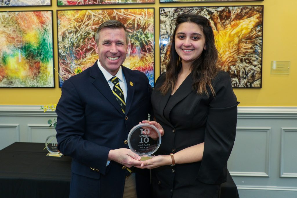 Amanda Metell stands with RMC President Michael Hill, holding a 10 Under 10 award