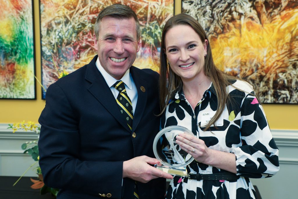 Alexandra Wilhelm stands with RMC President Michael Hill, holding a 10 Under 10 award