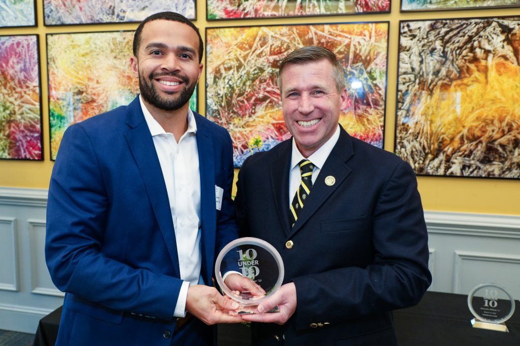 Korey Turner stands with RMC President Michael Hill, holding a 10 Under 10 award