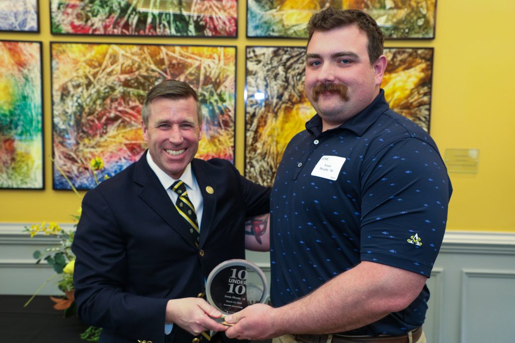 Sonny Murphy stands with RMC President Michael Hill, holding a 10 Under 10 award