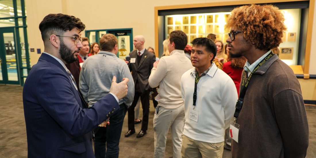 Two RMC Students listen to a volunteer during a networking reception during Edge Boot Camp