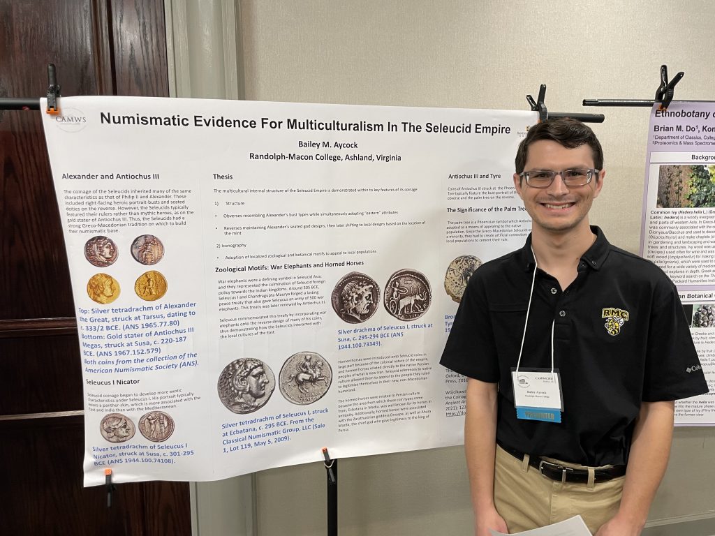 An RMC student wearing a polo stands in front of a research poster