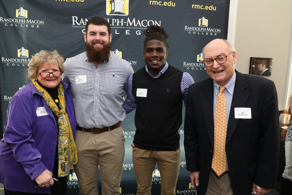Barclay and Rob DuPriest pose with two college students in front of an RMC backdrop