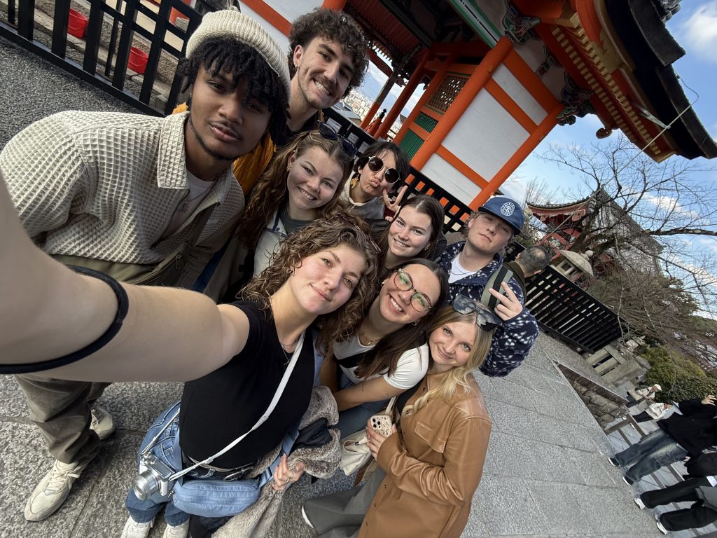 A group of students takes a selfie while visiting a Japanese shrine