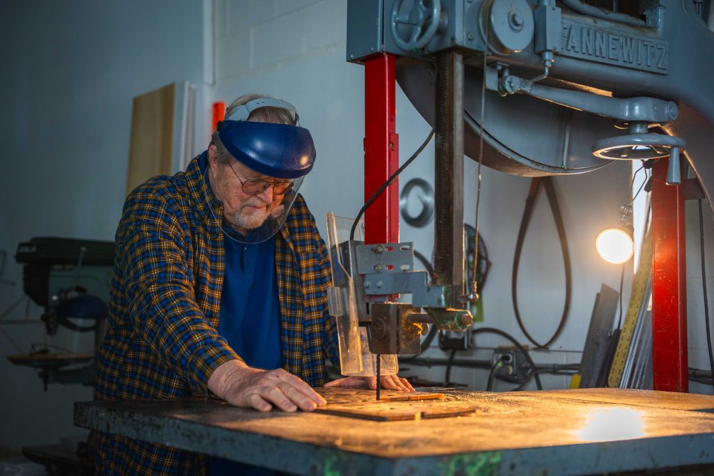 Jim Sanborn wears a protective face shield while operating a table saw