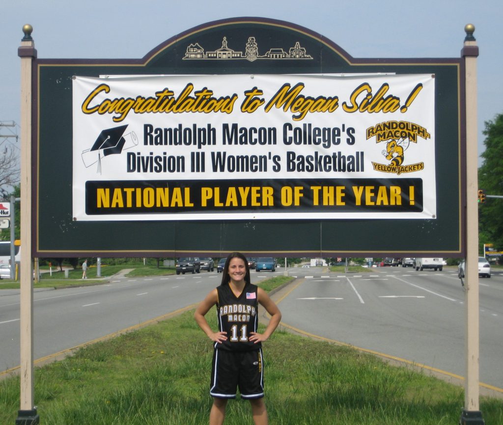 Megan Silva Schultz stands in front of a banner on England Street in Ashland congratulating her National Player of the Year honor