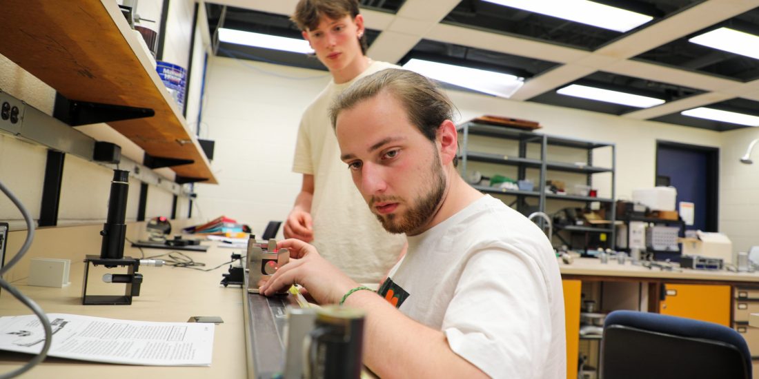 Two male students conducting experiments using lasers and mirrors