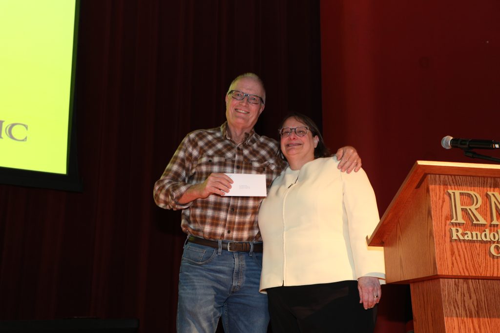 Dr. Chas. Gowan and Provost Alisa Rosenthal stand on the Blackwell stage holding a certificate