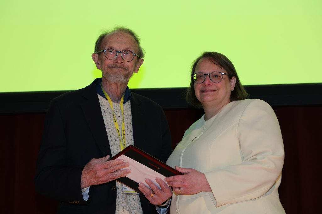 Dr. Joe Mattys and Provost Alisa Rosenthal stand on the Blackwell stage holding a certificate