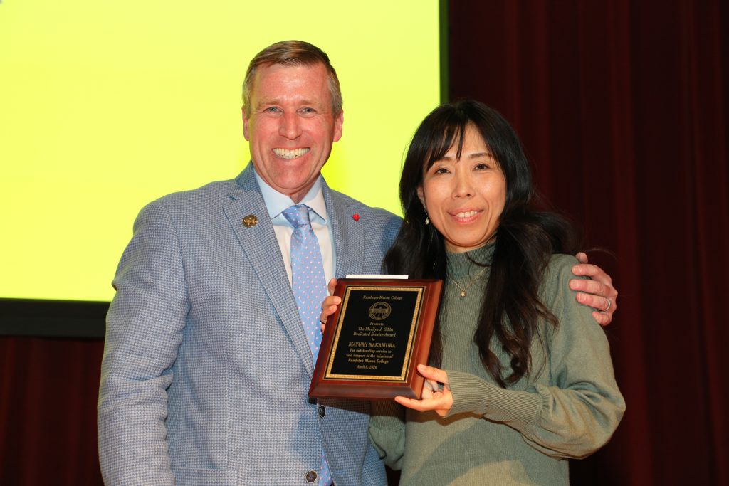 Mayumi Nakamura and President Michael Hill stand on the Blackwell stage holding a plaque
