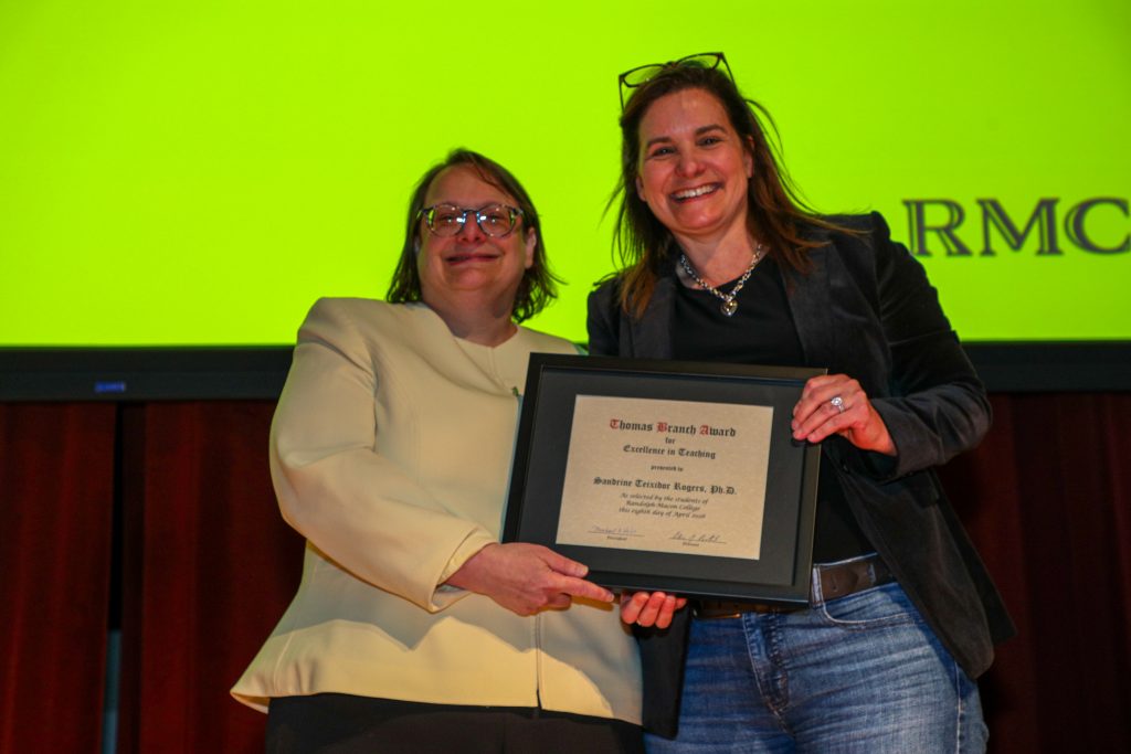 Dr. Sandrine Teixidor and Provost Alisa Rosenthal stand on the Blackwell stage holding a certificate