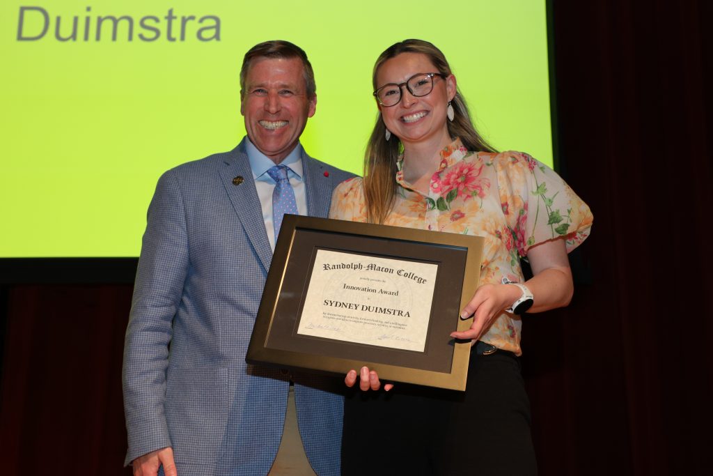Sydney Duimstra and President Michael Hill stand on the Blackwell stage holding a certificate