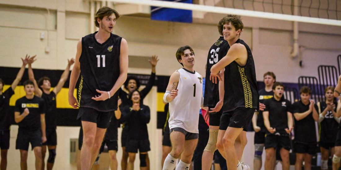 Members of RMC Men's Volleyball congratulate each other after a point inside Crenshaw Gymnasium as teammates celebrate in the background