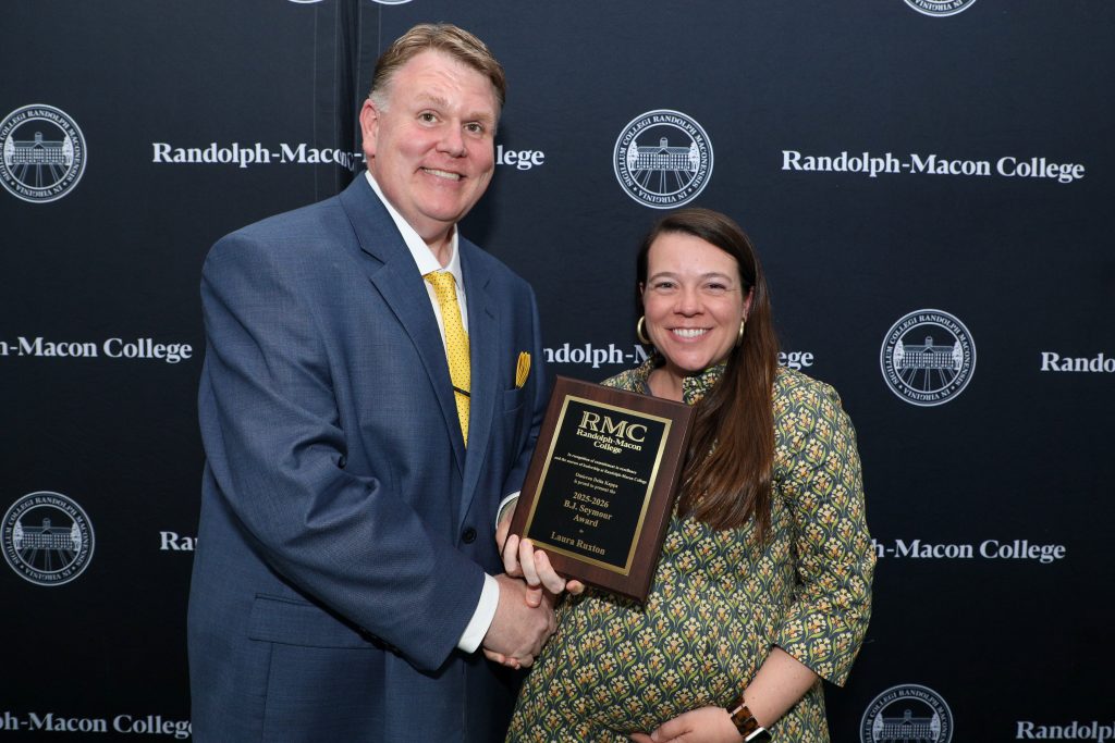 Laura Ruxton holds the BJ Seymour Award plaque and shakes hands with Dean James McGhee