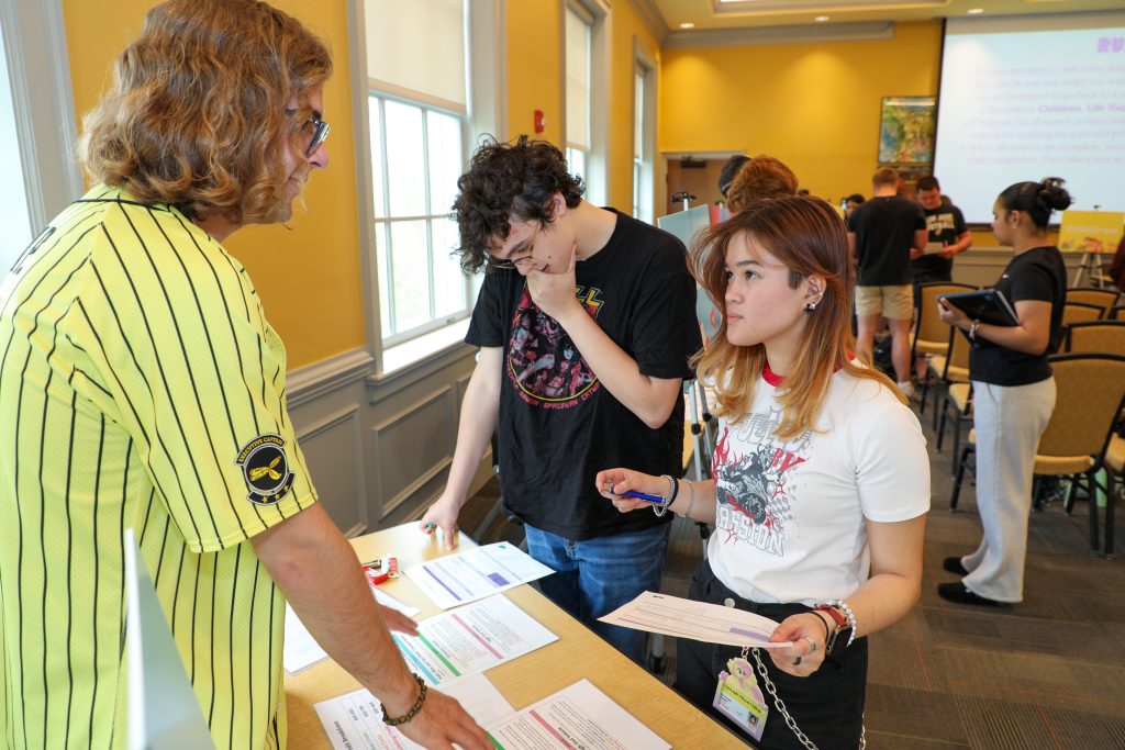 Two students hold papers and listen to a Captain explain their options during a "reality of money" workshop during a YJSS class