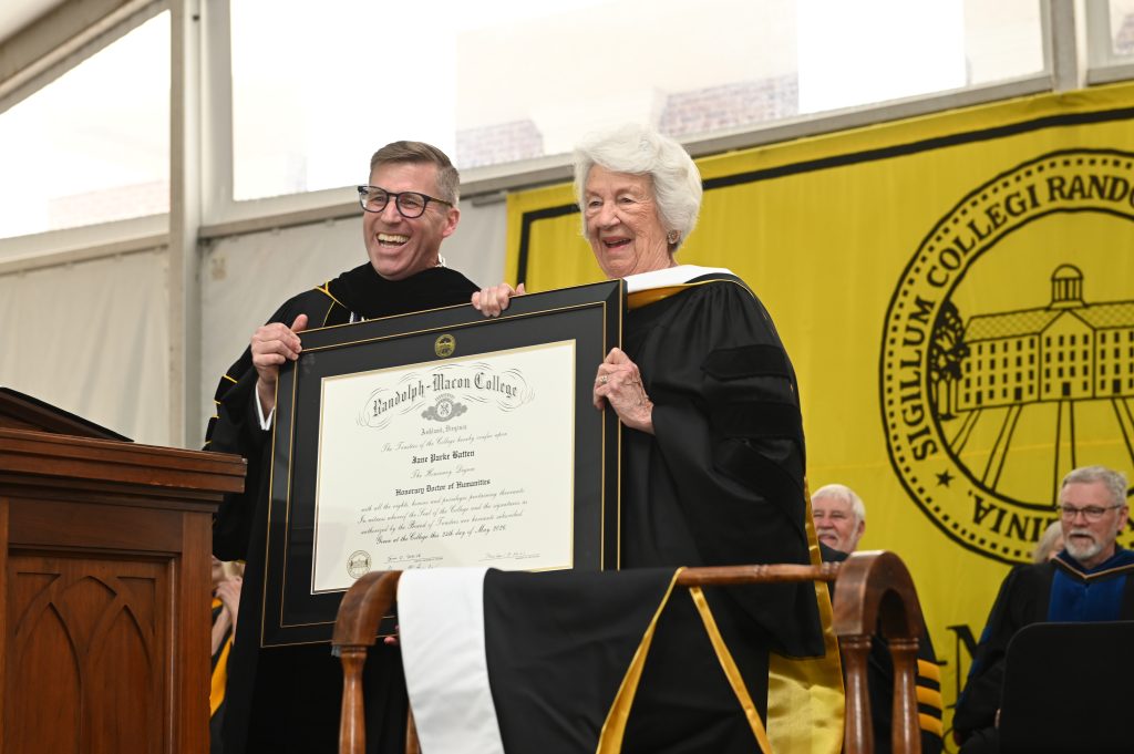 Jane Batten stands on the Commencement stage with President Michael Hill, both holding the diploma for her honorary degree