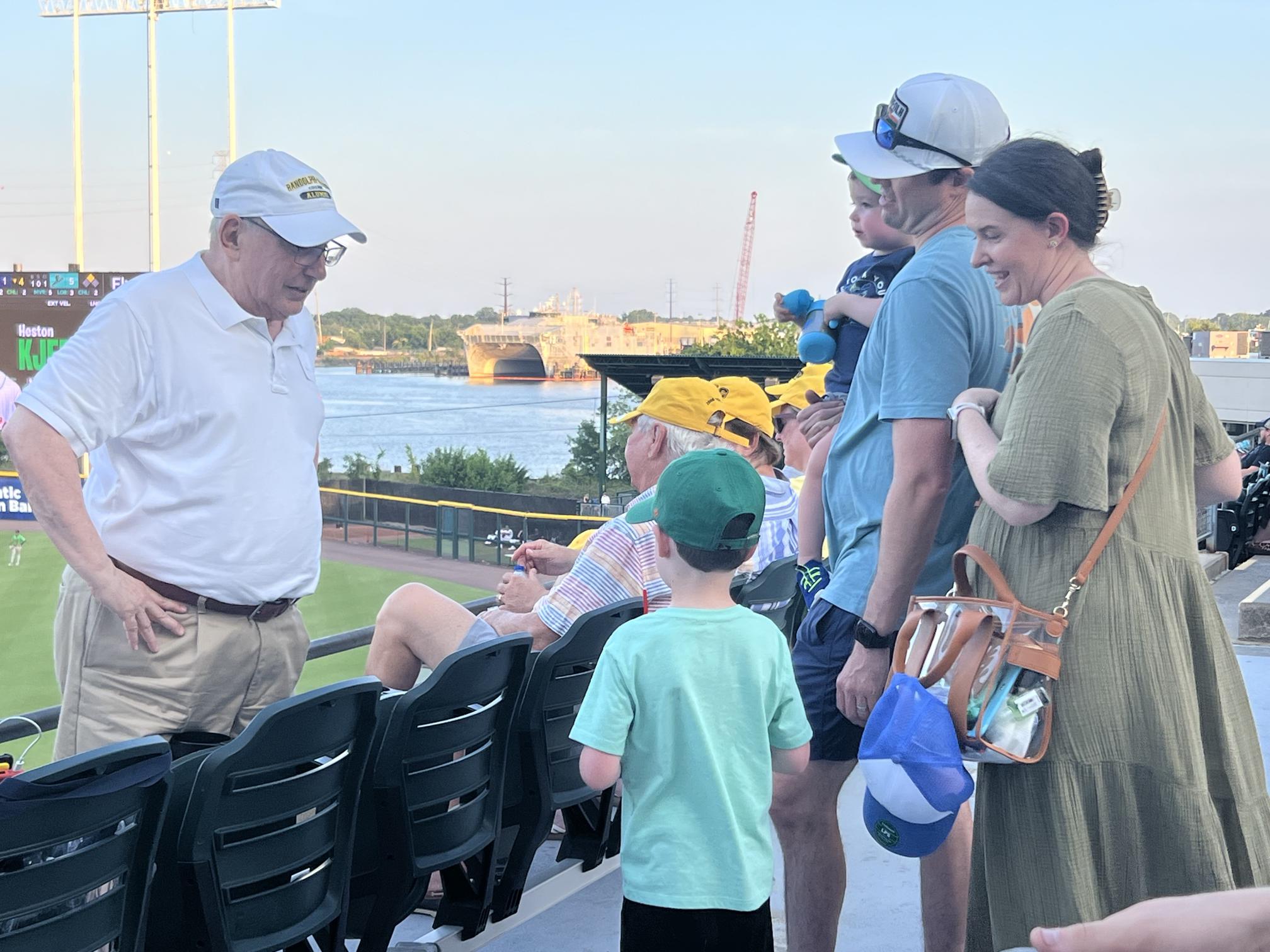 Individuals including a child, gather in the stadium at a Norfolk Tides baseball game.