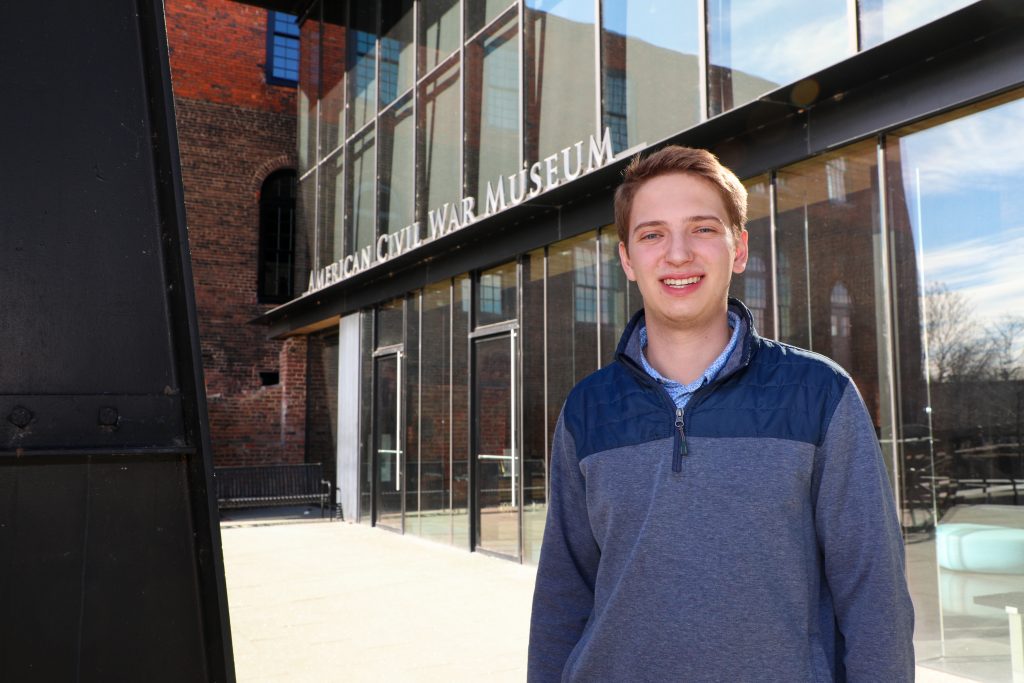 An RMC student stands smiling outside the entrance to the American Civil War Museum in downtown Richmond