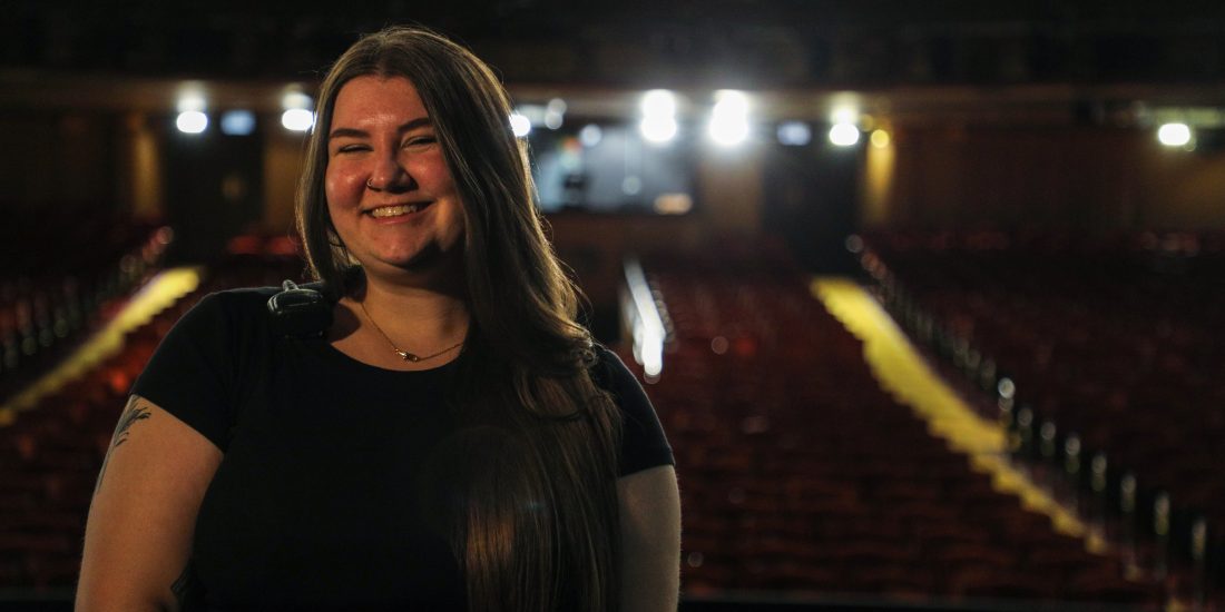 Katie Dodge smiles with the seats of a theater in the background