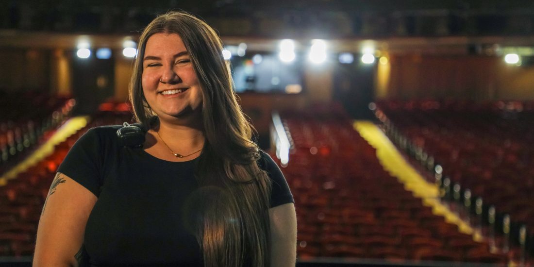 Katie Dodge smiles with the seats of a theater in the background