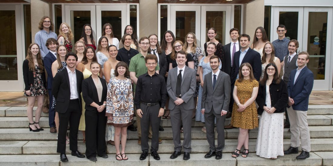 A group of students in professional dress poses in rows on the steps in front of the Center for the Performing Arts