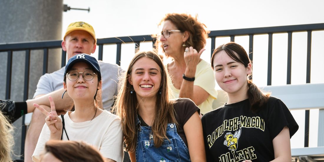 A group of students sit in the stands to watch an RMC football home game.