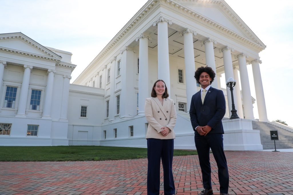 Two RMC students in business suits stand in front of the Virginia State Capitol