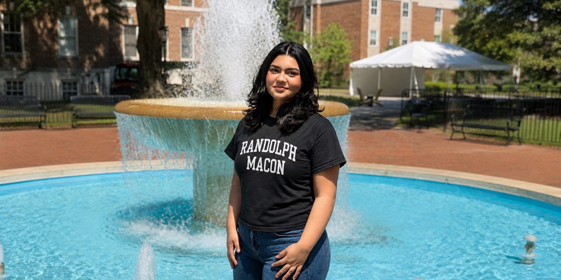 Ashleigh Flores stands in front of the fountain wearing a Randolph-Macon shirt
