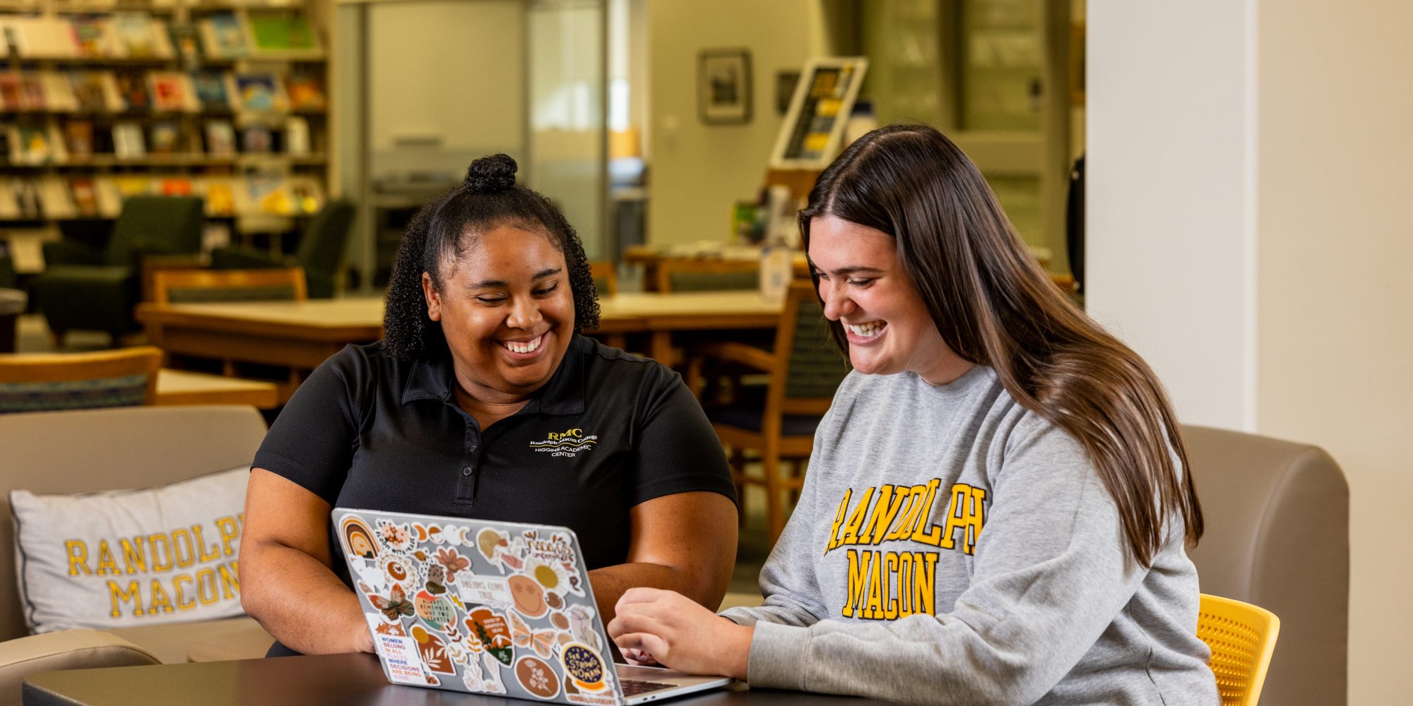 Two women from Center for Student Success staff in library, around a laptop