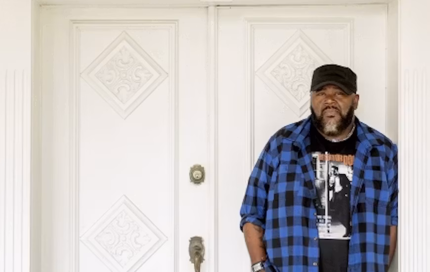 SA Cosby stands in front of a door to a brick building
