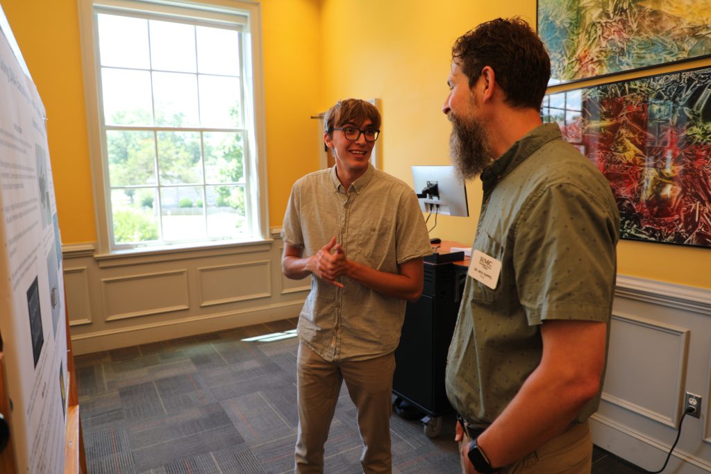 A student and professor discuss a poster during the 2026 SURF Symposium