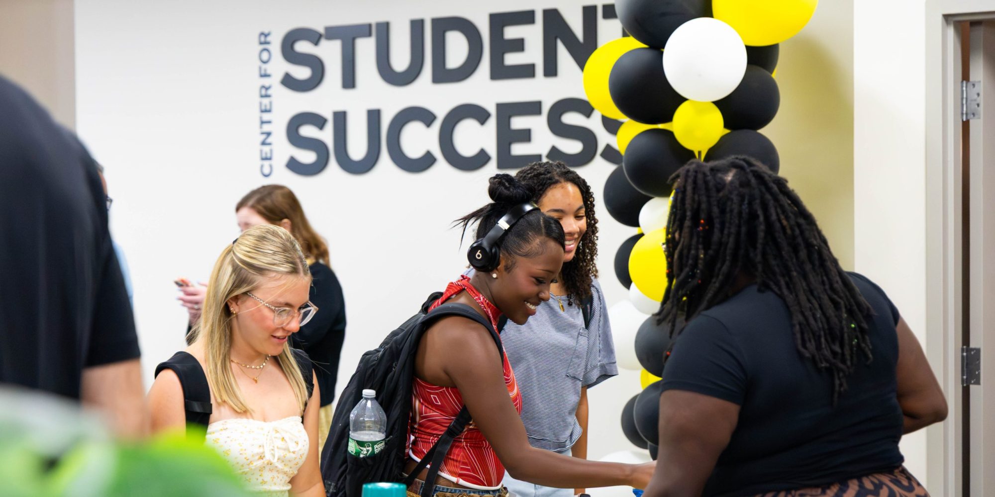 Students smile and talk under Center for Student Success sign at event