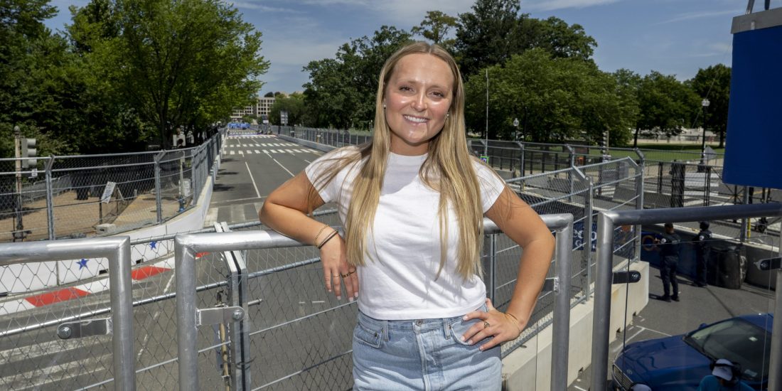 Emma Landis poses with the Washington, D.C. street course for the Freedom 250 Grand Prix in the background