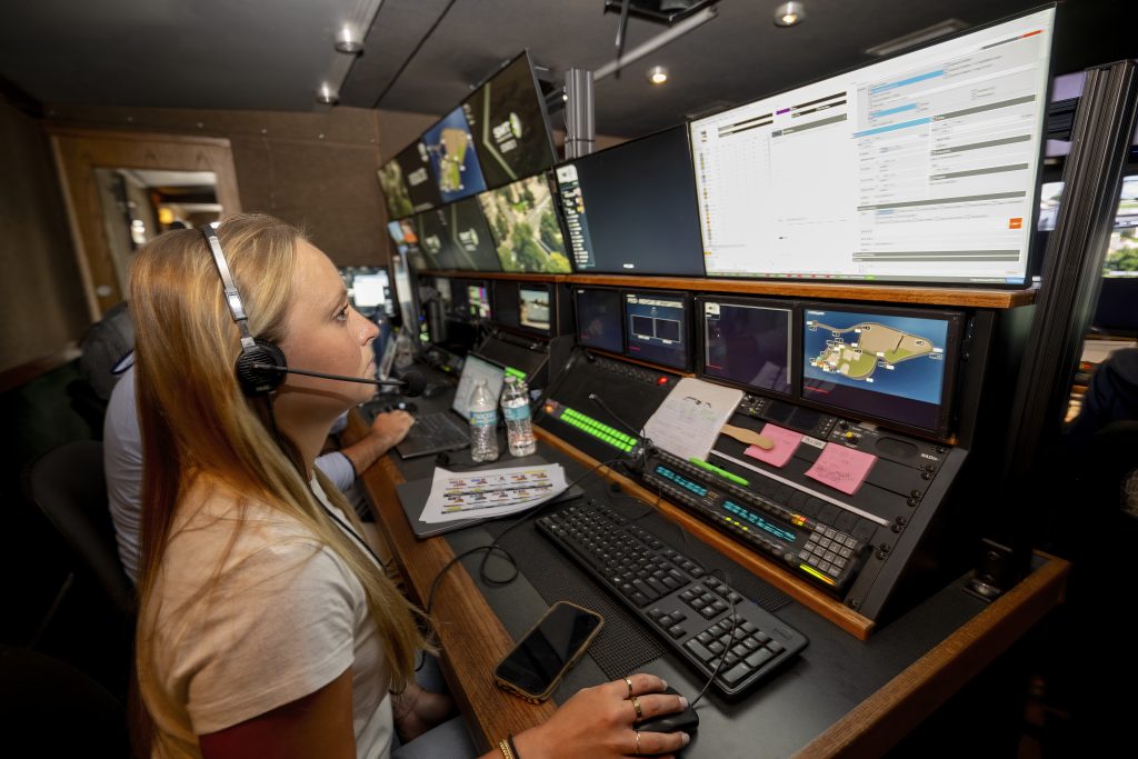 Emma Landis wears a headset inside a Fox Sports production truck, working on graphics during a broadcast