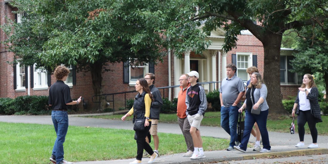 Perspective students and families are lead on a tour campus by a student tour guide.