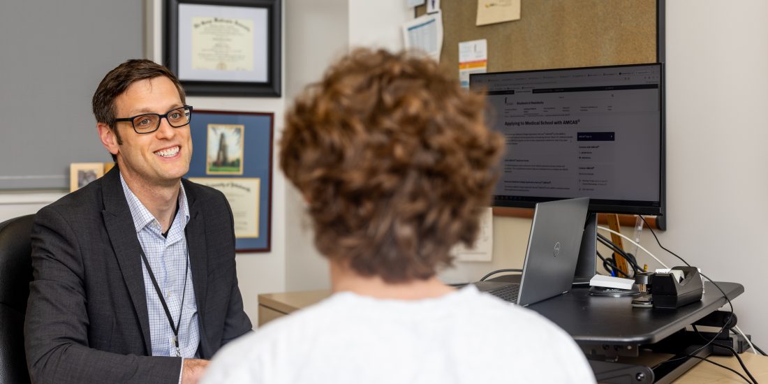 A member of the Career Development Team advising a student at a desk.
