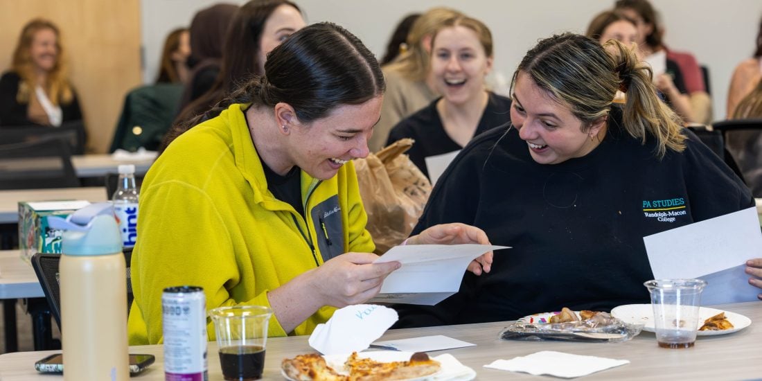 A student holding a paper reacts excitedly and points to her classmate's own paper