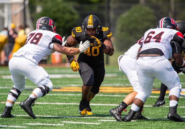 Jace DePriest runs down the field toward the camera past opponents.