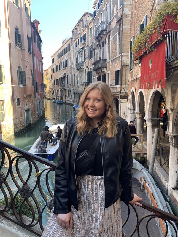 Taylor Ailtmar standing on a bridge overlooking a canal in Italy.