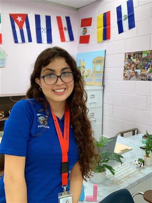 Alexandra Lugo '21 in her classroom wearing a blue Hermitage shirt and red lanyard